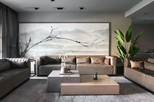 Grey living room with leather sofas, layered coffee tables, and a large mountain mural