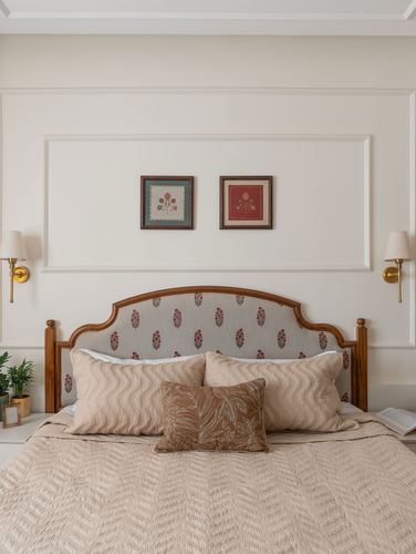 Bed with carved wood headboard, block-print fabric panel, symmetrical sconces and framed art above
