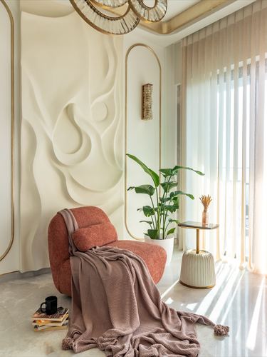 Terracotta boucle chair with mauve throw beside a sculptural white mural wall in sunlit living room