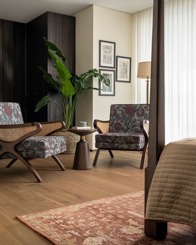 Cane-backed armchairs and side table beside a plant near a four-poster bed