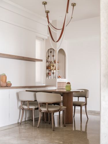 Dining nook with fluted wood table, cane chairs, and an arched display niche