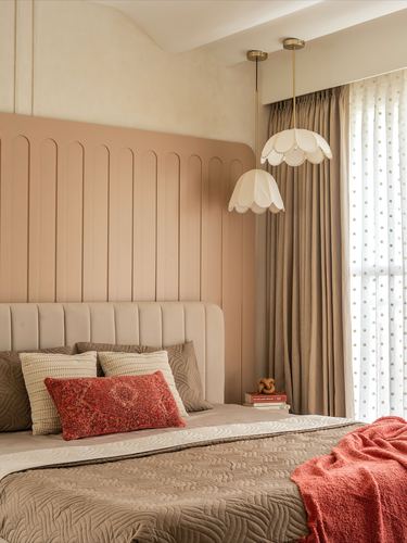 Bedroom with fluted pink arched headboard wall and scalloped pendant lights by curtained window