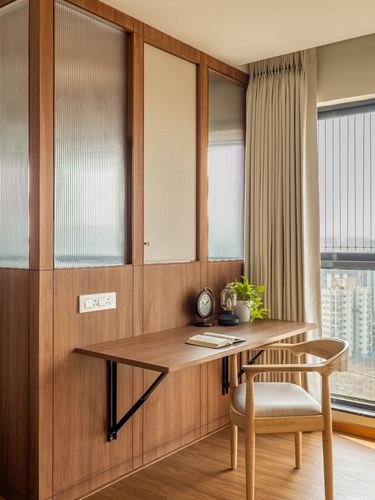 Wall-mounted wooden desk with chair beside window, wood-panelled wall with fluted glass inserts