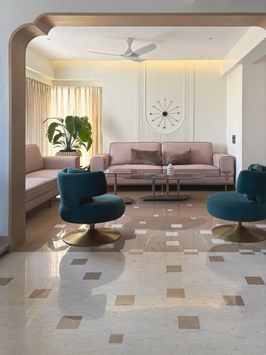 Living room with pink sofas, teal swivel chairs, marble floor, and a curved wooden archway