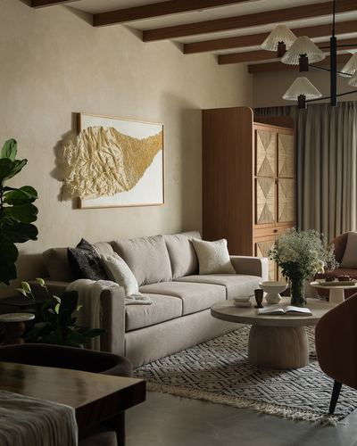 Beige living room with beamed ceiling, cane cabinet, textured art, and round stone coffee table