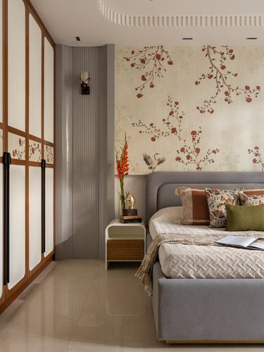 Bedroom with floral wallpaper headboard wall, grey upholstered bed, and wood-paneled wardrobe