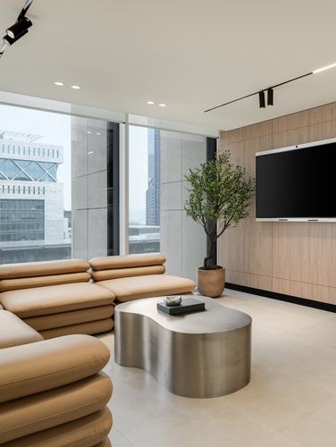 Curved tan leather sofa and sculptural metal coffee table in a minimalist office lounge with oak panelling