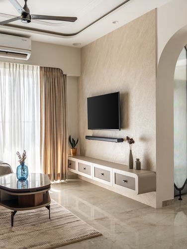 Beige living room with textured feature wall, floating tv unit, arched mirror niche and marble floor