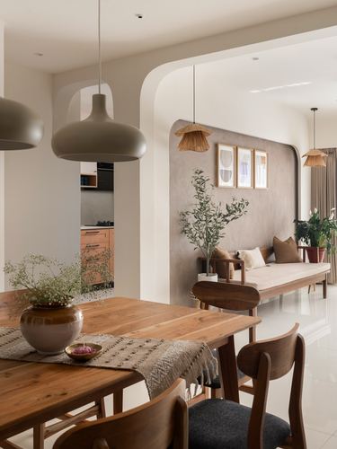 Dining table foreground with arched plaster niche and wooden bench beyond in warm-toned home