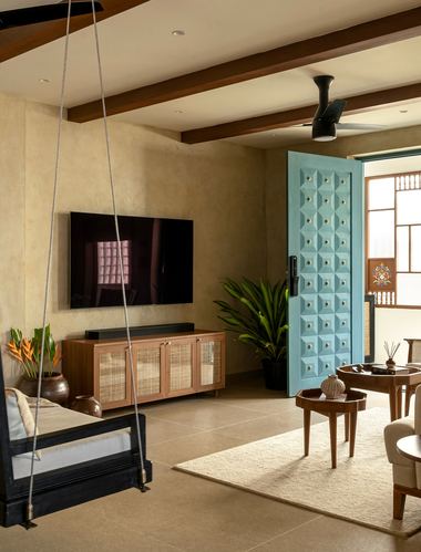 Living room with rope-hung wooden swing, tv console, and a studded blue door