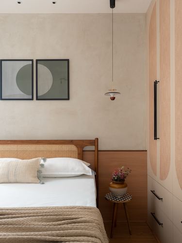Bedroom with cane headboard, wooden nightstand, pendant light, and textured plaster wall in Hyderabad apartment