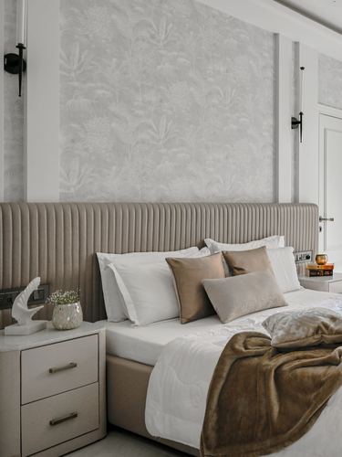 Bed with beige channel-tufted headboard, layered pillows, and botanical wallpaper backdrop.