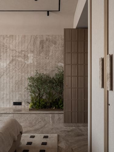 Bedroom corner with stone wall, built-in planter, and grid-textured wooden wardrobe door