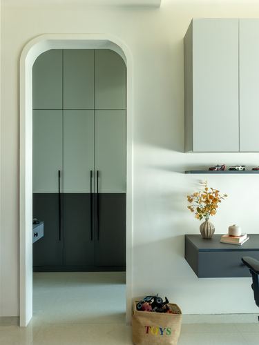 Arched doorway leading to a green-and-charcoal wardrobe, beside a floating desk with flowers.