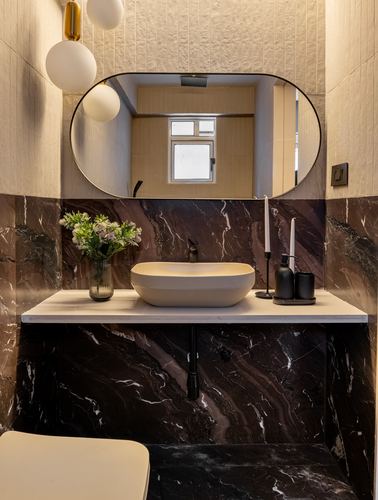 Bathroom vanity with oval mirror, vessel sink, and dark marble counter and cladding