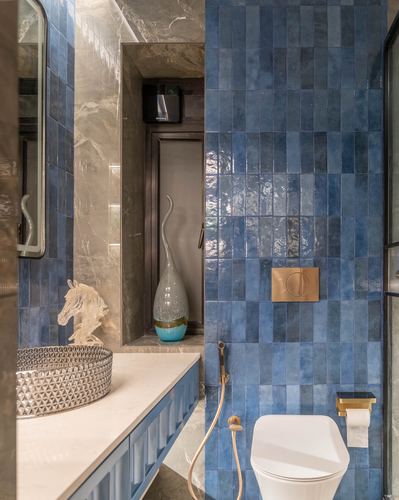 Bathroom corner with vertical blue tile wall, marble vanity nook, and brass fixtures